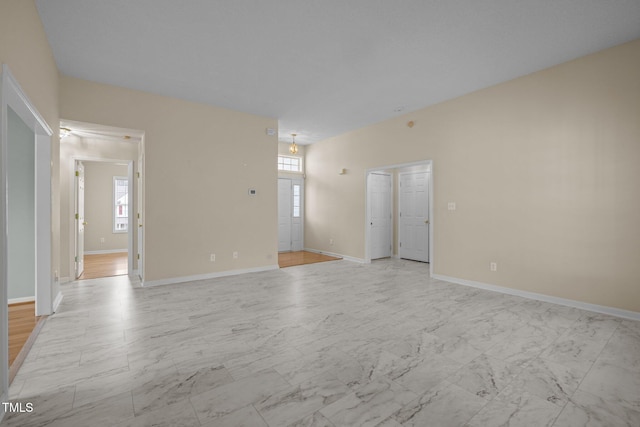 unfurnished living room with marble finish floor and baseboards