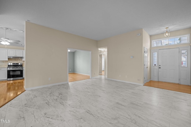 entryway with a ceiling fan, marble finish floor, and baseboards