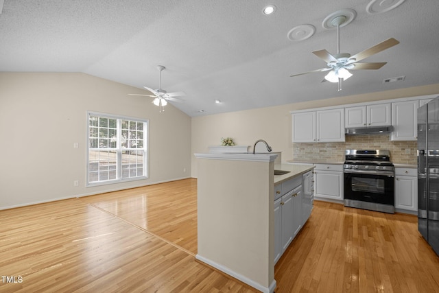 kitchen with lofted ceiling, light wood-style floors, stainless steel gas range oven, and visible vents