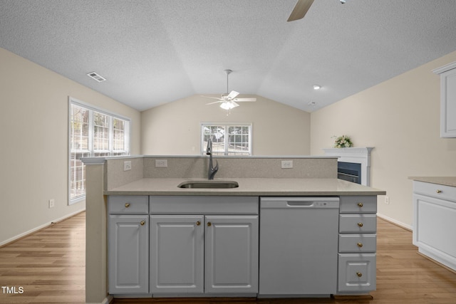 kitchen featuring visible vents, lofted ceiling, white dishwasher, gray cabinets, and a sink