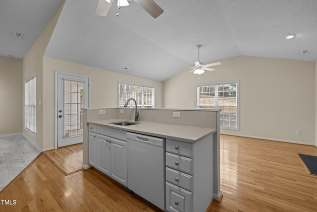 kitchen with light wood finished floors, dishwasher, vaulted ceiling, gray cabinets, and a sink