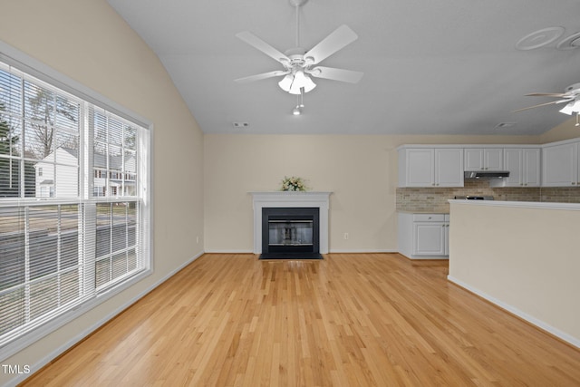 unfurnished living room with visible vents, a ceiling fan, lofted ceiling, a fireplace with flush hearth, and light wood-style floors