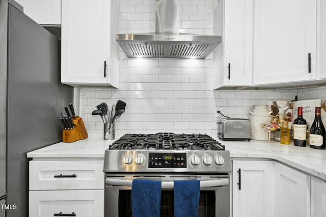 kitchen with tasteful backsplash, white cabinets, light stone counters, stainless steel appliances, and exhaust hood