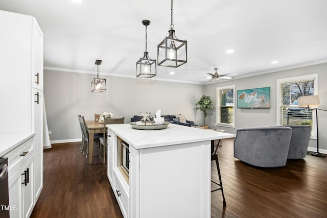 kitchen featuring dark wood-style flooring, ornamental molding, a breakfast bar area, and a kitchen island