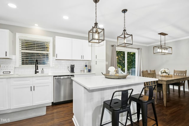 kitchen featuring dark wood finished floors, light countertops, crown molding, stainless steel dishwasher, and a sink