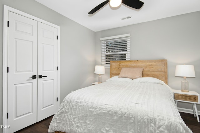 bedroom featuring baseboards, visible vents, dark wood finished floors, ceiling fan, and a closet