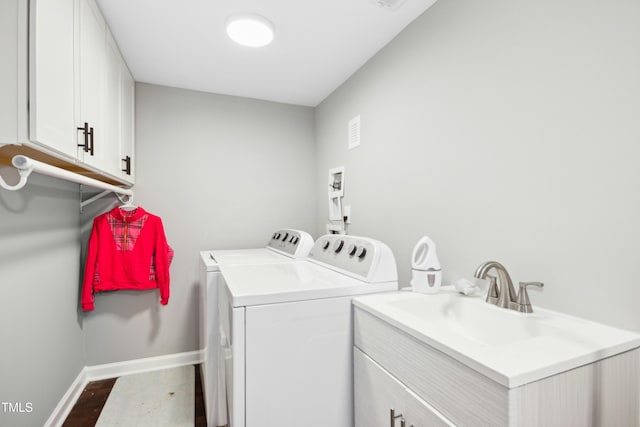 laundry area with cabinet space, baseboards, washer and clothes dryer, wood finished floors, and a sink