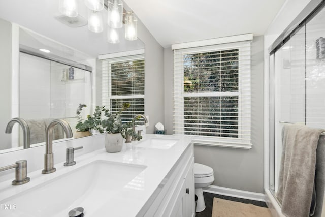 full bathroom featuring double vanity, a stall shower, a sink, and toilet