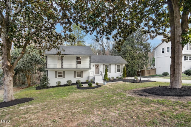 tri-level home featuring a balcony and a front lawn