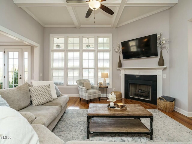 living area with coffered ceiling, baseboards, and wood finished floors