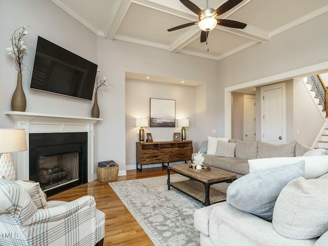 living room with stairway, coffered ceiling, wood finished floors, and a ceiling fan