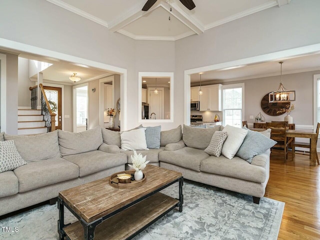 living area featuring light wood-style flooring, ornamental molding, coffered ceiling, beamed ceiling, and stairs