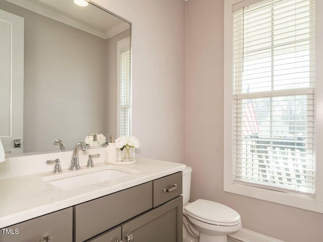 half bathroom with ornamental molding, vanity, and toilet