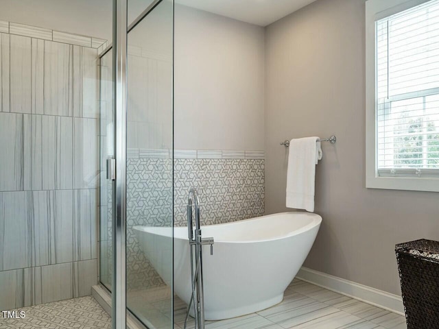 full bath with a freestanding bath, a shower stall, and baseboards