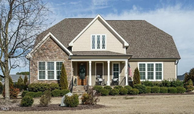 craftsman house featuring stone siding, a porch, and a shingled roof