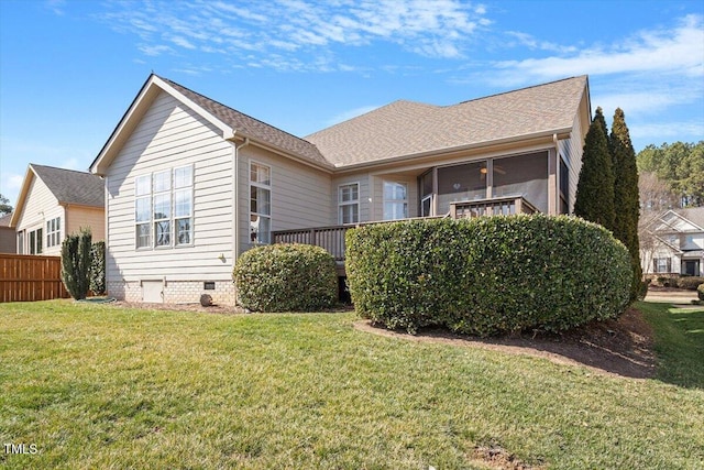 rear view of house featuring fence, a sunroom, a lawn, roof with shingles, and crawl space