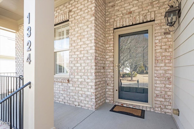 property entrance featuring a porch and brick siding