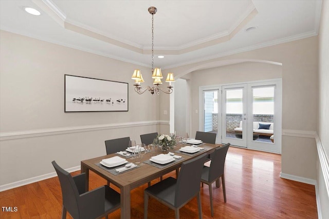 dining area featuring wood finished floors, a raised ceiling, and baseboards