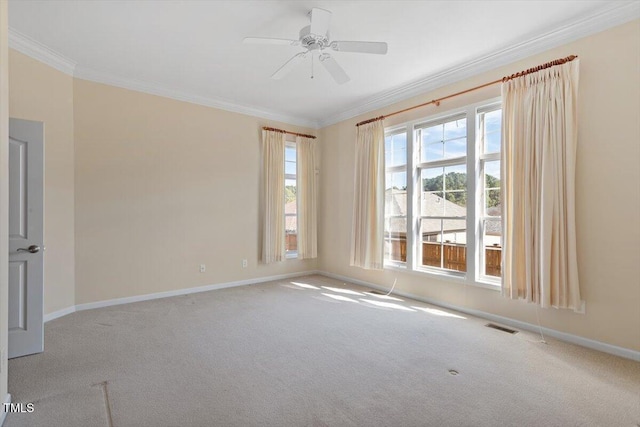 carpeted empty room featuring ornamental molding, a ceiling fan, visible vents, and baseboards