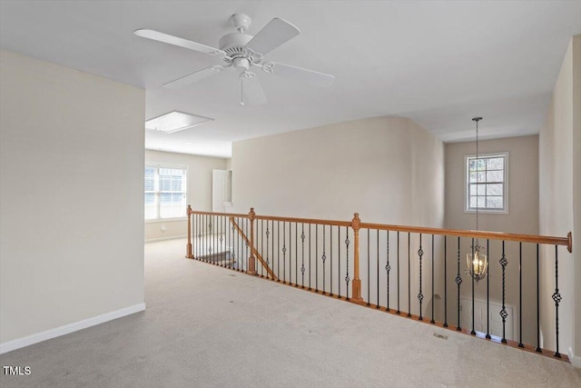 empty room with carpet floors, ceiling fan, baseboards, and a wealth of natural light