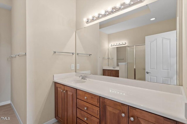 bathroom featuring a shower stall, baseboards, and vanity