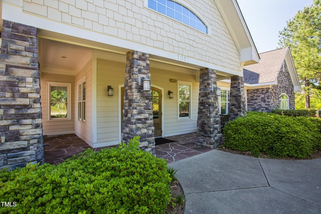 entrance to property featuring a shingled roof and stone siding