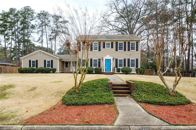 colonial-style house with a front lawn and fence