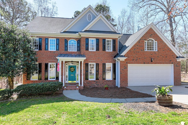 colonial home with concrete driveway, brick siding, a front yard, and a shingled roof