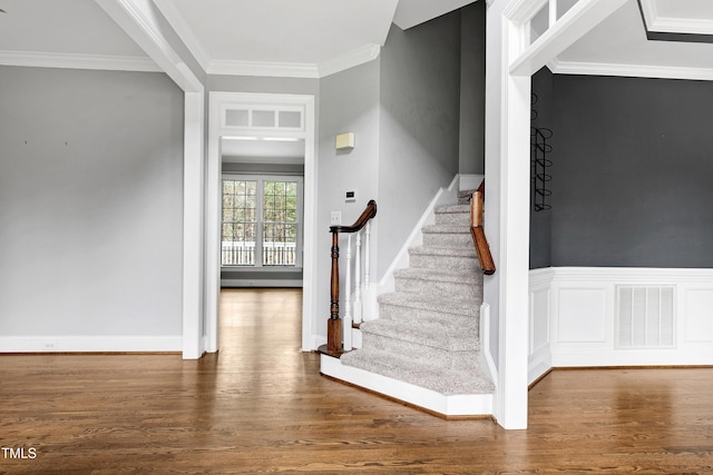 stairway featuring visible vents, ornamental molding, a wainscoted wall, and wood finished floors