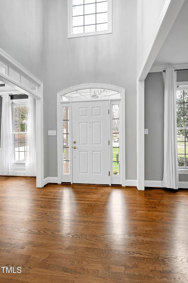 entrance foyer with a towering ceiling, baseboards, and wood finished floors