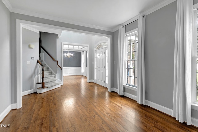 foyer featuring ornamental molding, dark wood finished floors, stairway, baseboards, and a chandelier