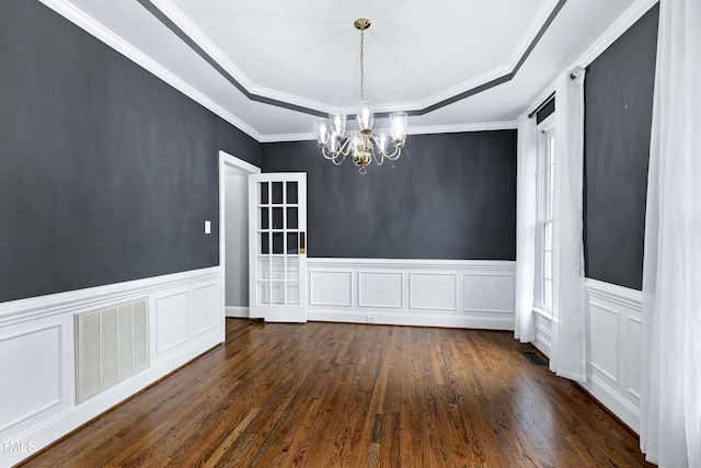 unfurnished dining area with visible vents, a tray ceiling, dark wood-style floors, a healthy amount of sunlight, and a chandelier