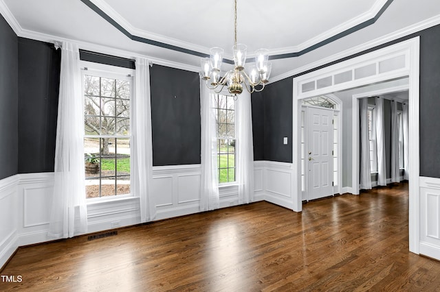 interior space with visible vents, a chandelier, ornamental molding, wainscoting, and wood finished floors