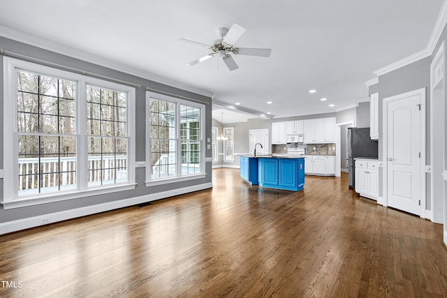 kitchen featuring blue cabinetry, freestanding refrigerator, white cabinetry, crown molding, and white microwave