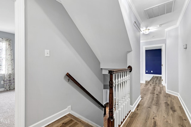 staircase featuring visible vents, baseboards, wood finished floors, and crown molding