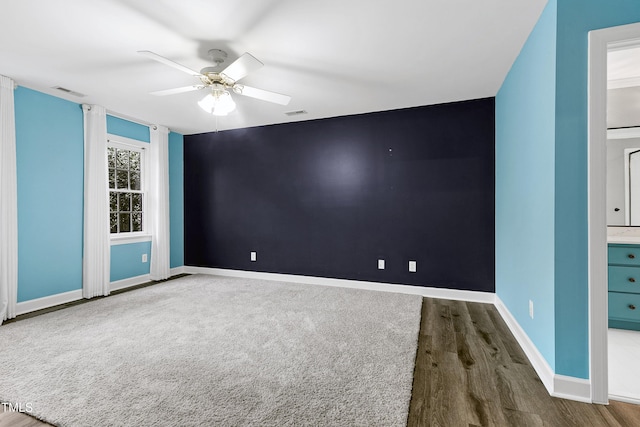 empty room featuring visible vents, baseboards, wood finished floors, and a ceiling fan