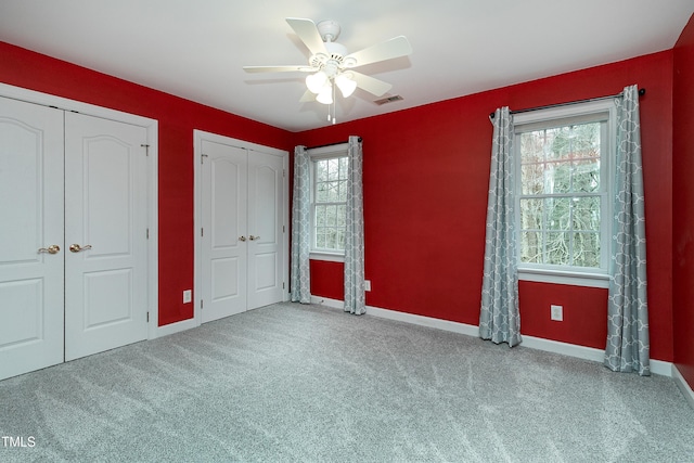 unfurnished bedroom with visible vents, multiple windows, multiple closets, and carpet floors