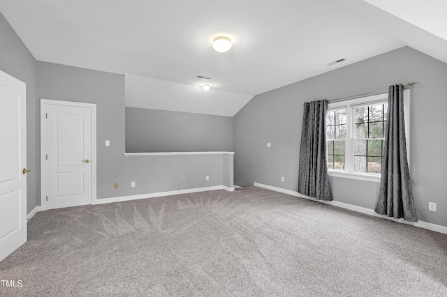 additional living space with visible vents, baseboards, carpet flooring, and vaulted ceiling