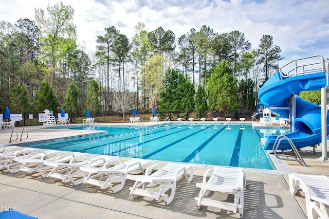 pool featuring a patio area, fence, and a water slide