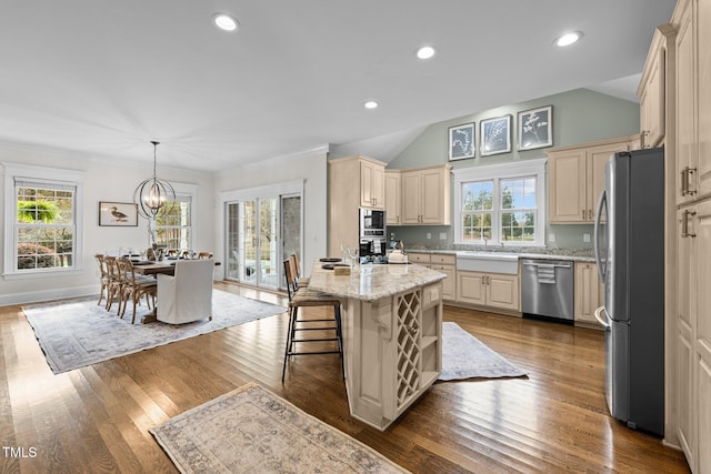 kitchen with plenty of natural light, dark wood-type flooring, light stone countertops, stainless steel appliances, and cream cabinetry