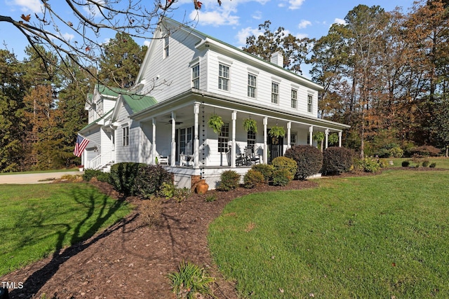 country-style home featuring ceiling fan, covered porch, a garage, a front lawn, and a chimney