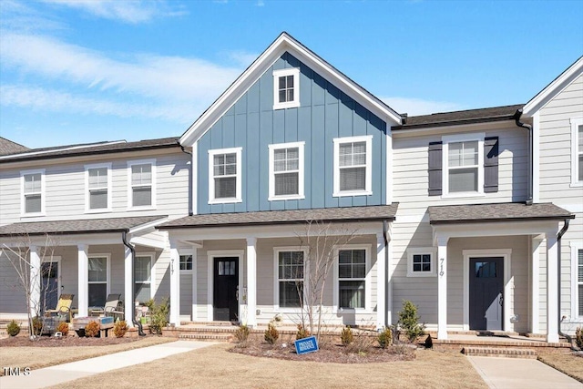 townhome / multi-family property with covered porch, a shingled roof, and board and batten siding