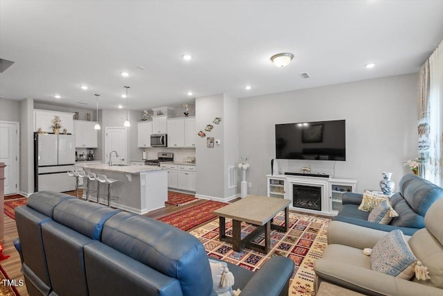 living room with a fireplace, visible vents, wood finished floors, and recessed lighting