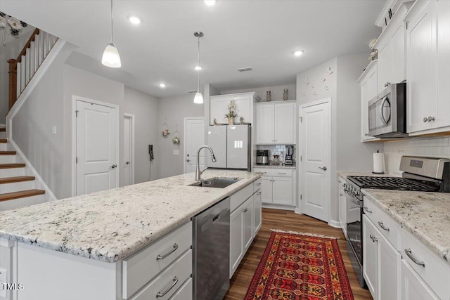 kitchen with stainless steel appliances, dark wood-type flooring, a kitchen island with sink, white cabinets, and a sink