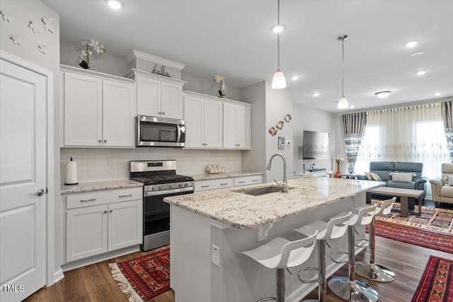 kitchen featuring open floor plan, stainless steel appliances, a sink, and decorative backsplash