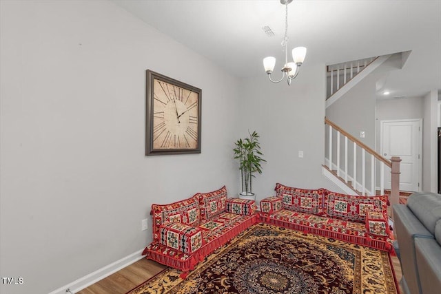 living room with stairs, baseboards, a chandelier, and wood finished floors