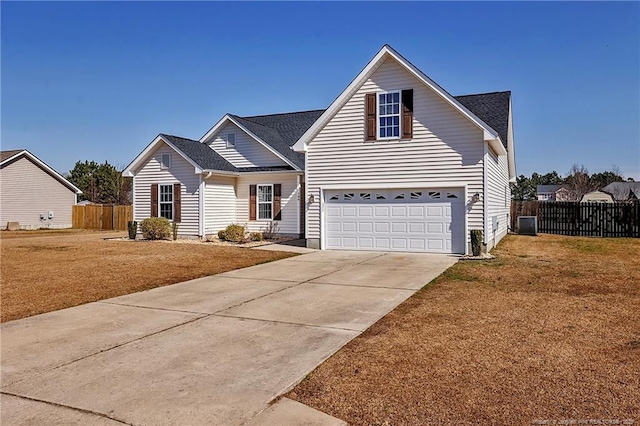 traditional-style home featuring concrete driveway, an attached garage, central AC, fence, and a front lawn