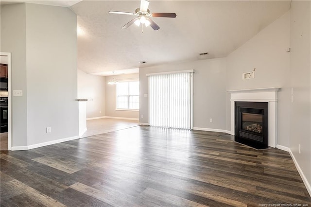 unfurnished living room with baseboards, a fireplace with flush hearth, dark wood-style flooring, vaulted ceiling, and ceiling fan with notable chandelier