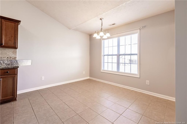 unfurnished dining area with baseboards, visible vents, and a notable chandelier