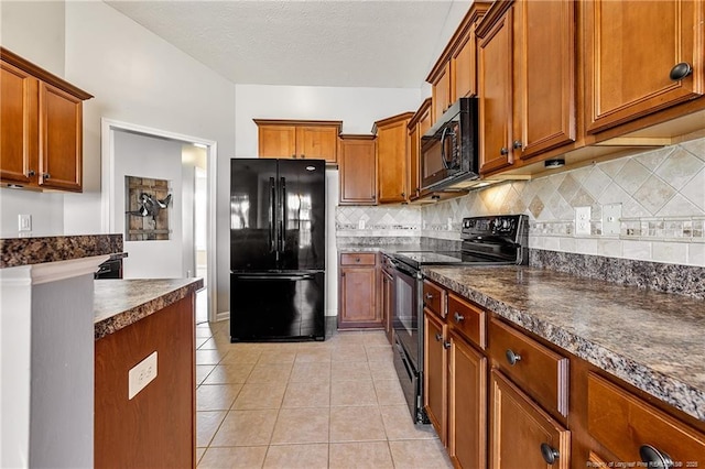 kitchen featuring light tile patterned floors, dark countertops, backsplash, brown cabinetry, and black appliances